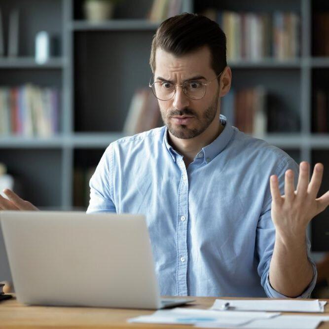 A man with a confused expression after his computer crashes unexpectedly.